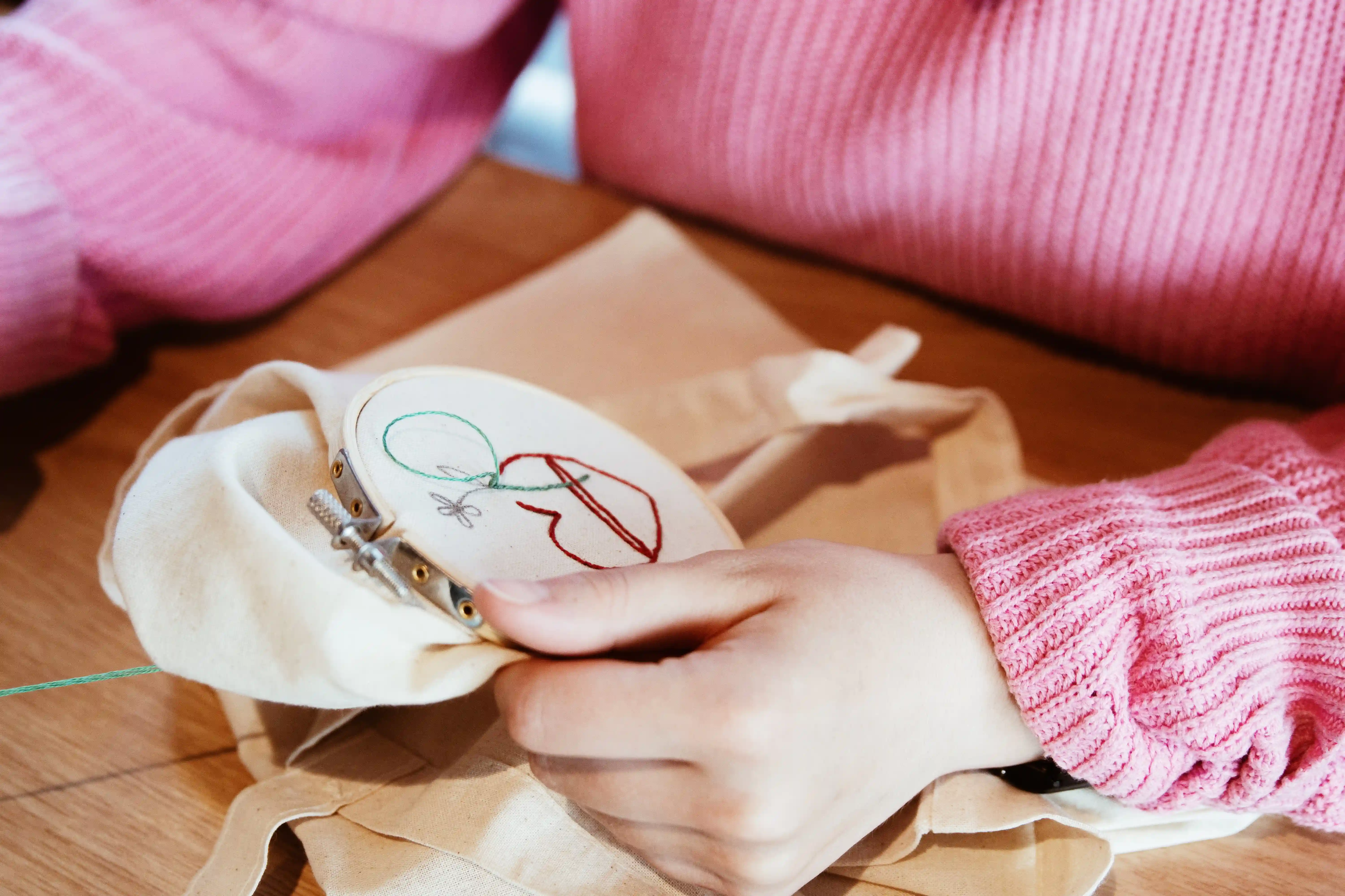 Hands embroidering a design on a canvas tote in an embroidery hoop
